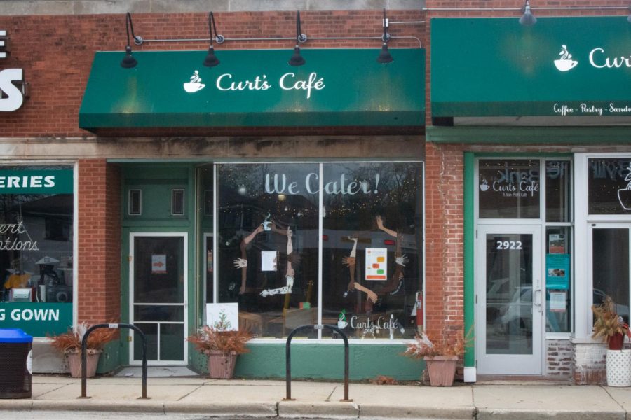 The storefront of Curt’s Café, a brick building with a green awning and a glass window.
