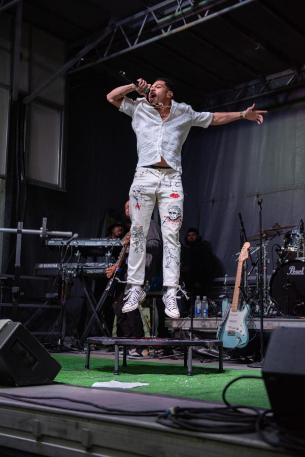 Taylor Bennett sings into a microphone while bouncing on a small trampoline.