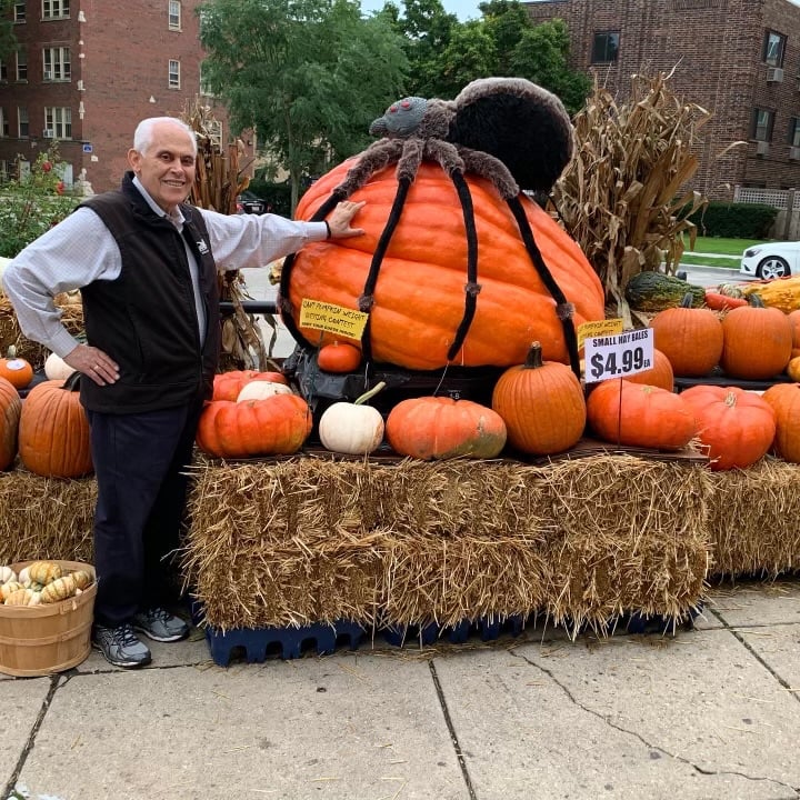 Thomas Douvikas, the owner of D&D Finer Foods, stands next to a pile of pumpkins.