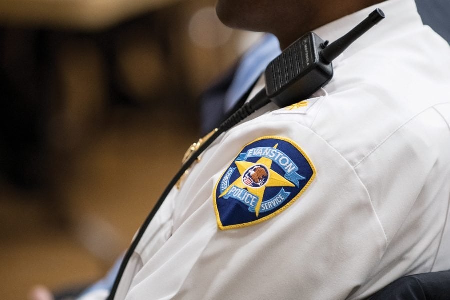 A close-up photo of a police officer’s embroidered crest on their white button-down shirt uniform.