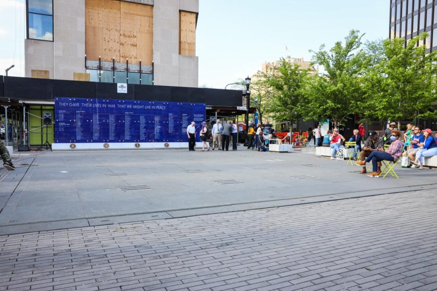 An empty paved space outdoors is flanked by people on its sides.