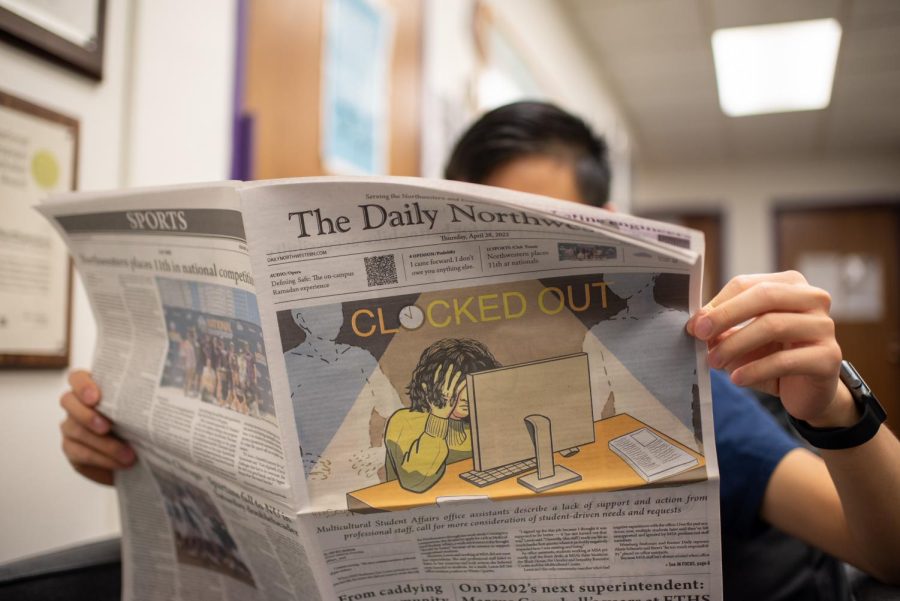 A reader holds up an edition of The Daily that reads “Clocked Out” on its cover.