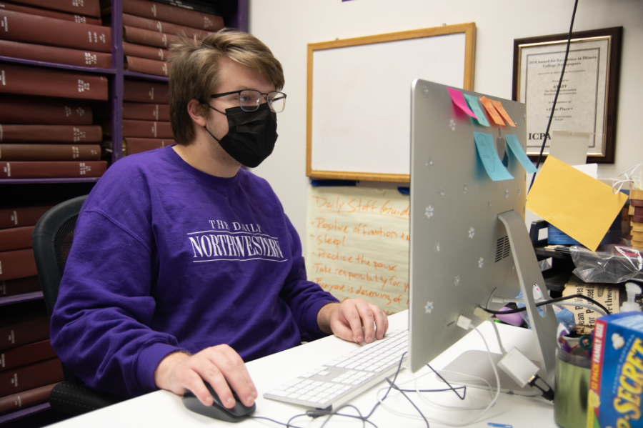 Editor-in-chief Jacob Fulton sits in front of a computer, dressed in a purple sweatshirt that reads The Daily Northwestern.