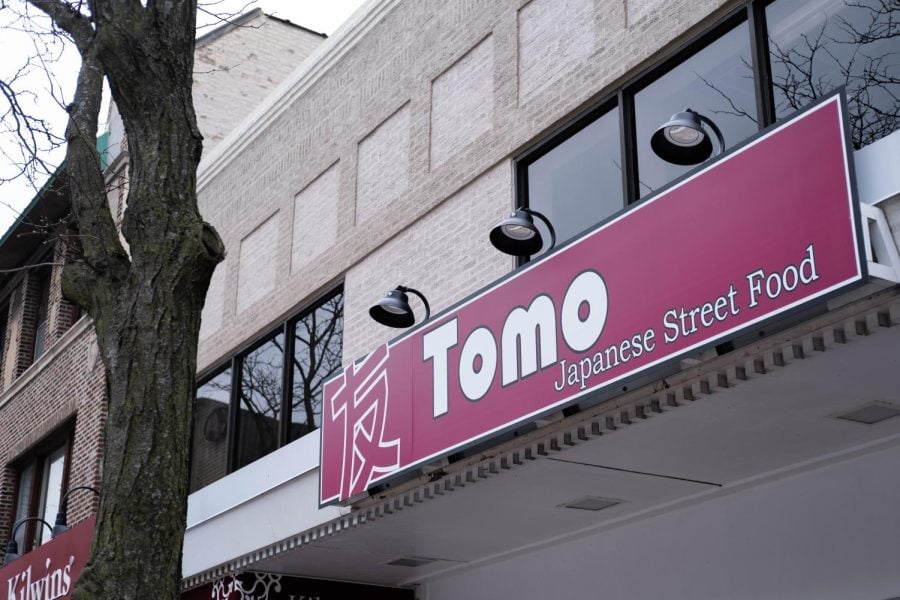 The+exterior+of+Tomo+Japanese+Street+Food.+A+red+sign+has+the+restaurant%E2%80%99s+name.