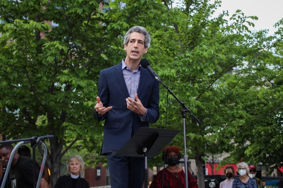 Mayor Daniel Biss gestures in front of a microphone.