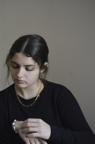 A woman looking at a bracelet of shells on her wrist