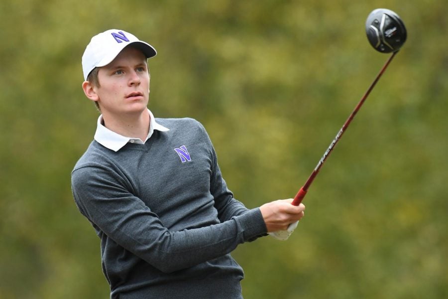A golf player in a gray sweater finishes their swing at the tee.