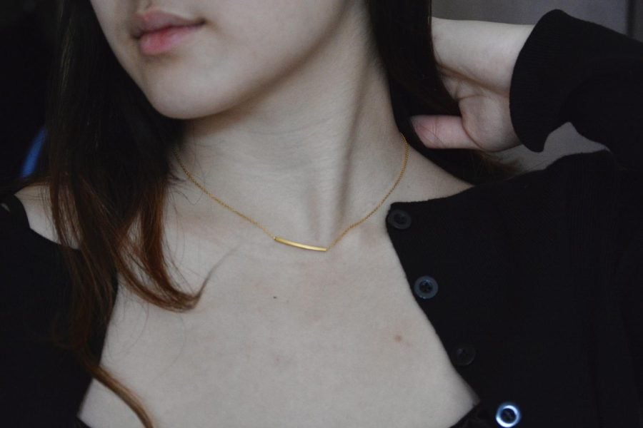 A gold necklace sits on a woman’s neck.