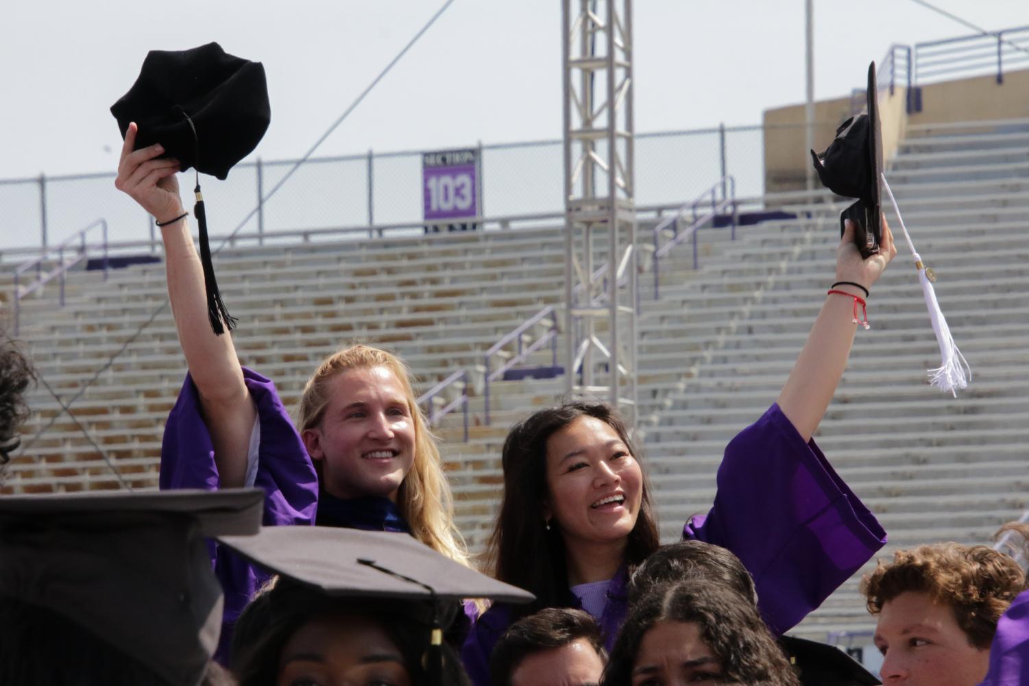 Two students wave their caps amid a sea of students.