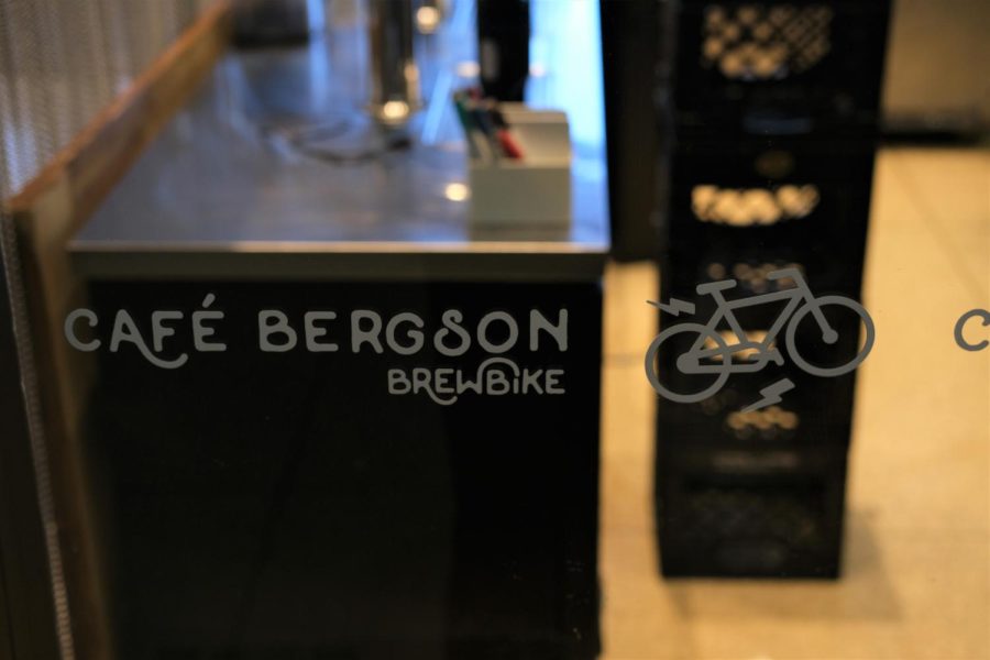 Brewbrike’s logo is to the right of Cafe Bergson’s logo on a pane inside the shop.