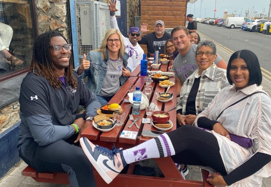 A group of people wearing Northwestern gear sit at a picnic table at a restaurant.