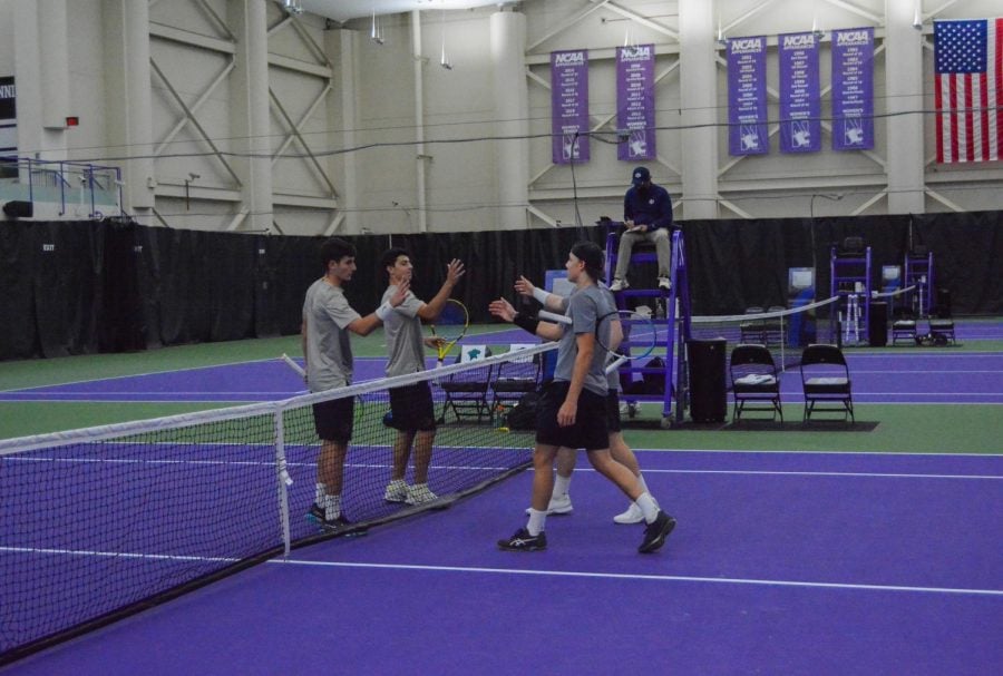 Two pairs of tennis players cross a purple court to shake hands with each other.