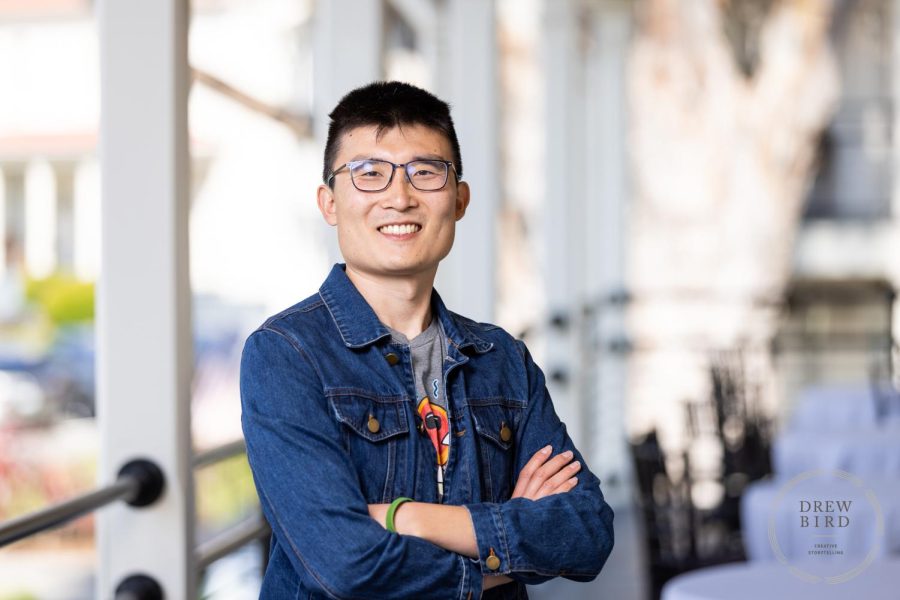 Jason Wang smiling and wearing a jean jacket while standing with his arms crossed.