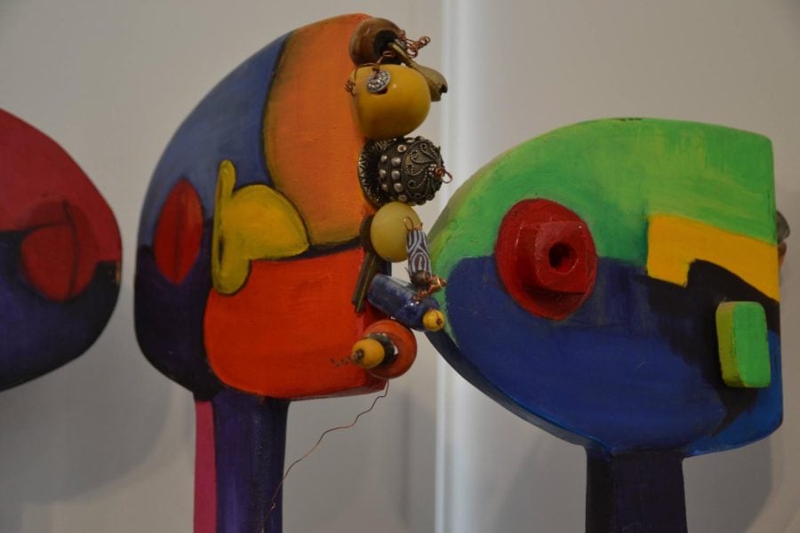 Beads are attached to colorful wooden statues that resemble humans.