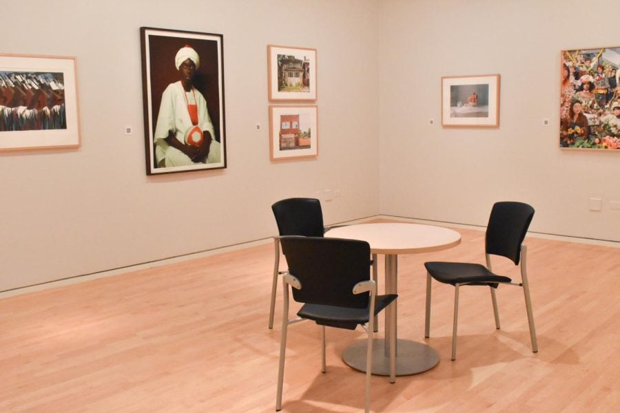 A white circular table with black chairs surrounded by framed images on white wall.
