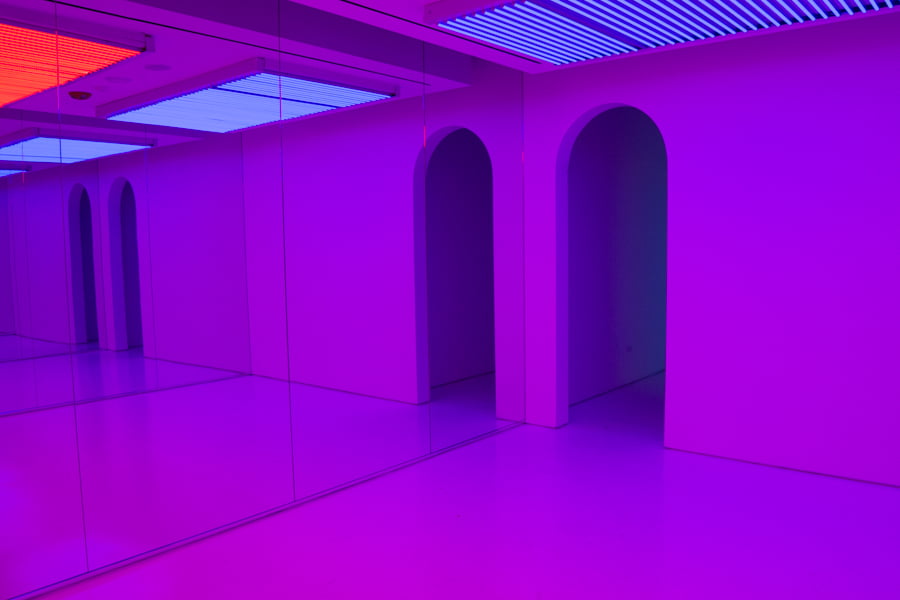 Room with mirrors submerged in purple hue.