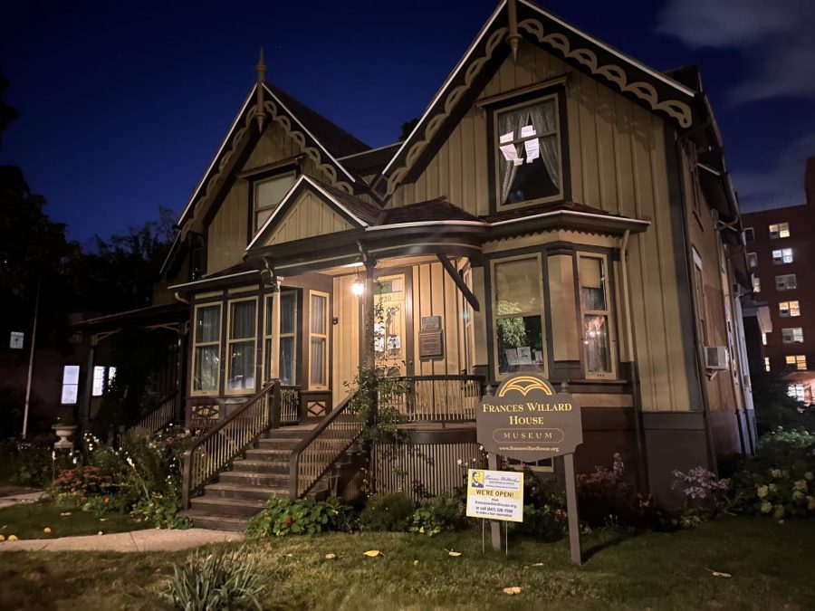 A photo of the Frances Willard House Museum. A brown paneled house set in front of the night sky.