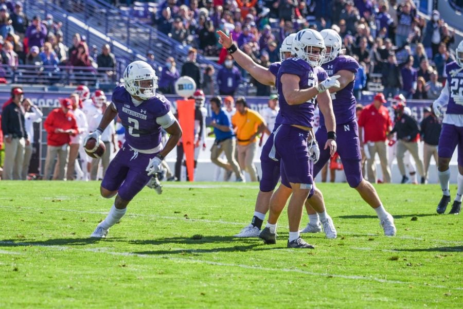 Players in purple uniforms celebrate a big play on a football field.