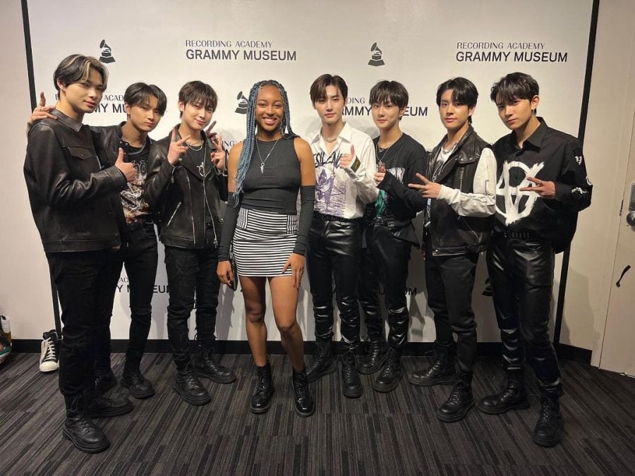 Ashlee stands with members of K-pop boy group ENHYPEN in front of Grammy backdrop.