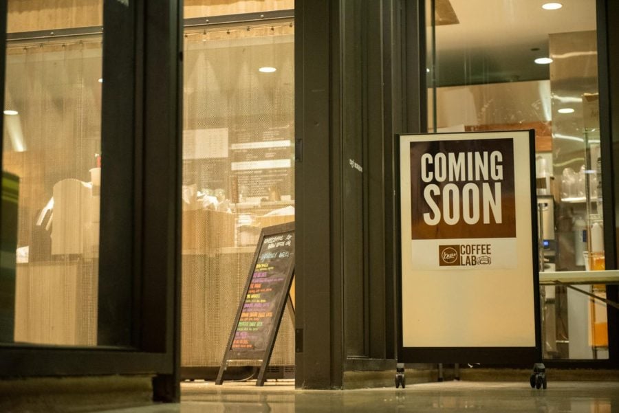 “Coming soon” sign sits outside a window and a cafe space.