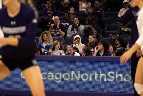 A person wearing headphones looks at athletes in the foreground and speaks into a microphone.