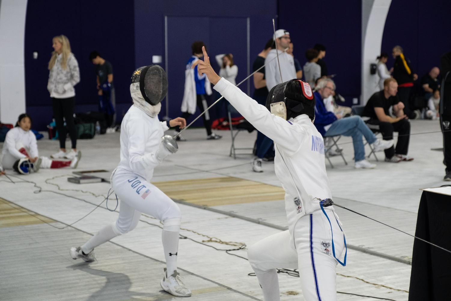 Two fencers move towards each other with weapons raised.