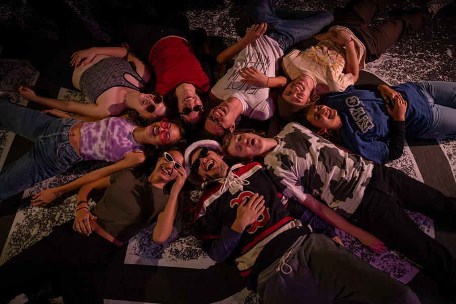 A group of people lie on the ground in a circle.
