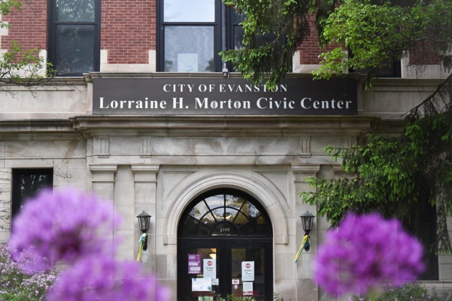A photo of the entrance of Lorraine H. Morton Civic Center in the daytime with two purple flowers out of focus in the camera.