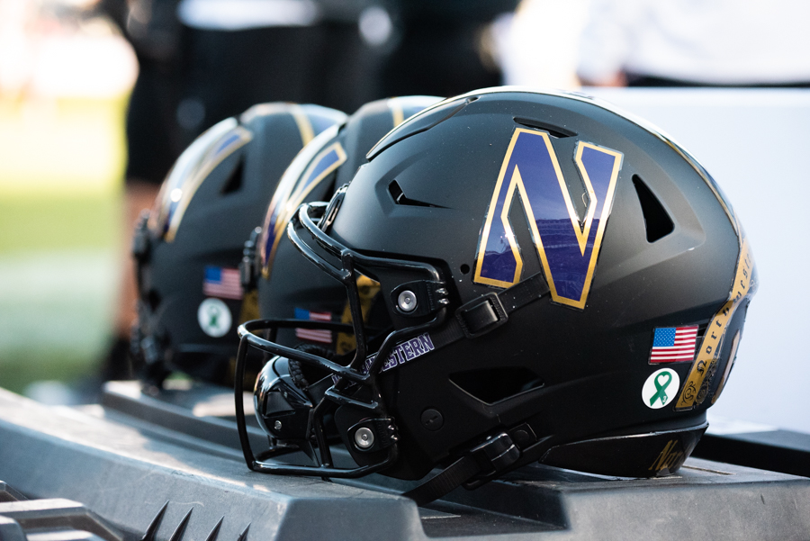 Three black football helmets with gold and purple ‘N’s on the side.