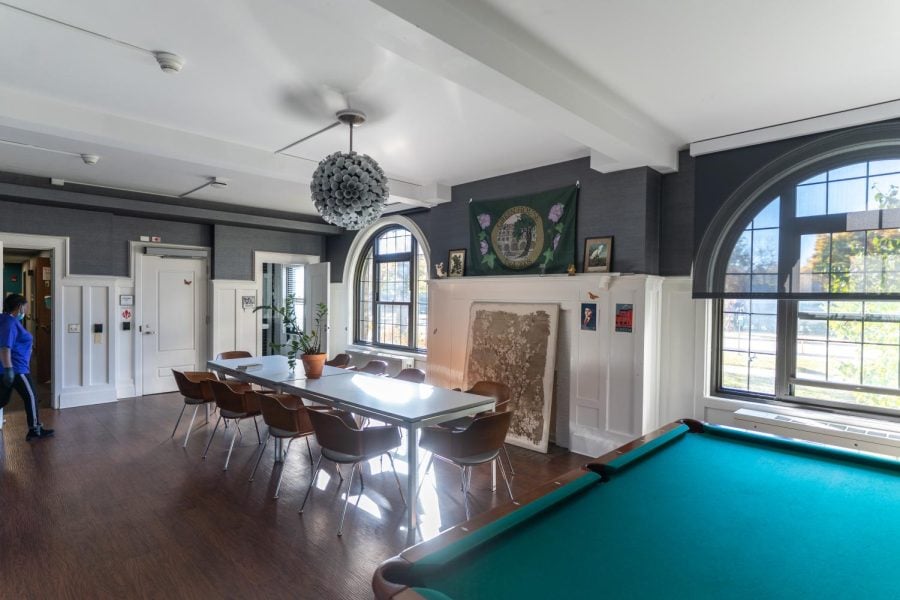A room in the Green House with a long dining table, pool table and large windows.