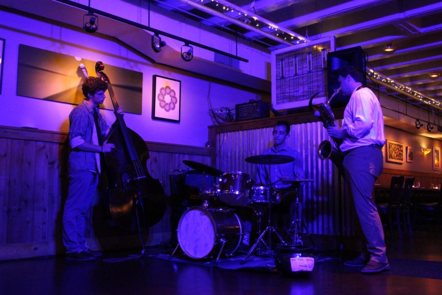 Three people playing instruments in a purple glow.