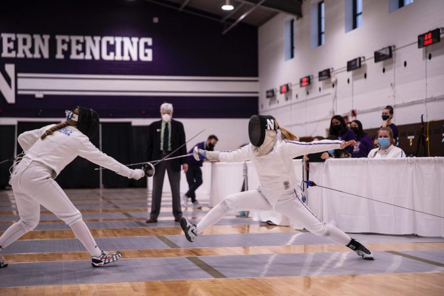 A fencer wearing white and purple gear battles in an epee bout.