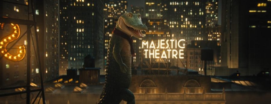 A CGI crocodile wears a brown jacket. Behind him, a display of lights read “Majestic Theater.”