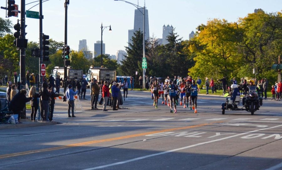 Runners in colorful clothing race across the curve of gray concrete pavement.