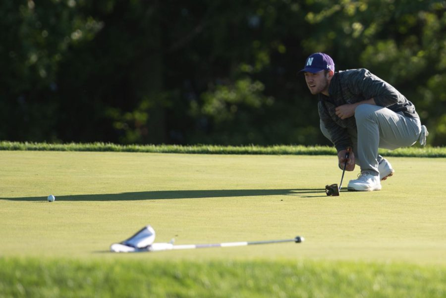 A golfer crouches down and looks forward to the ball.