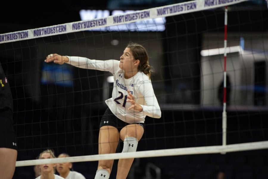 A volleyball player wearing a white jersey with the number ‘21’ on it follows through after hitting the ball.