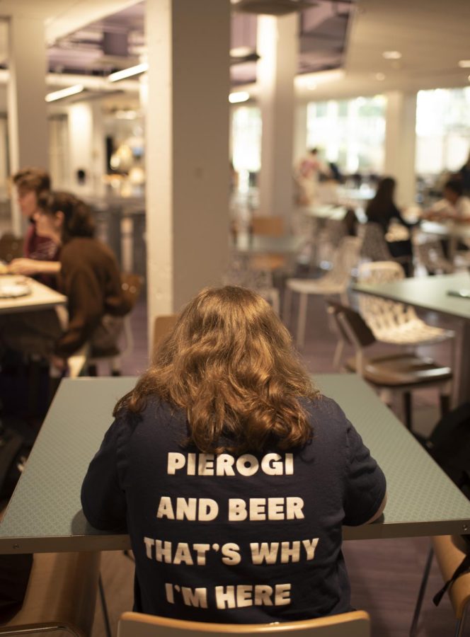 An individual sits with her back turned to the camera. The inscription on her shirt says: “Pierogi and beer, that’s why I’m here.”