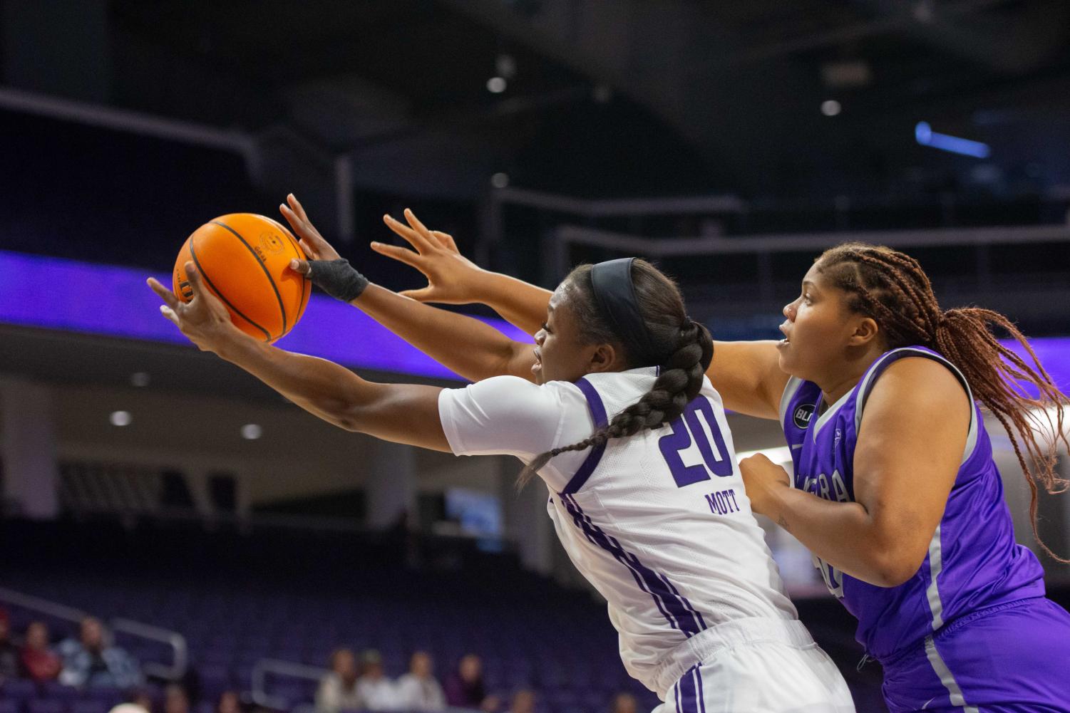 A basketball player in white catches the ball to the left while someone in purple tries to reach for it.