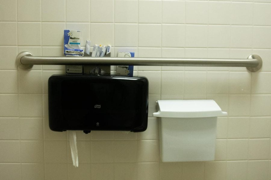 Toilet+paper+dispenser+with+menstrual+products+on+top+of+it.