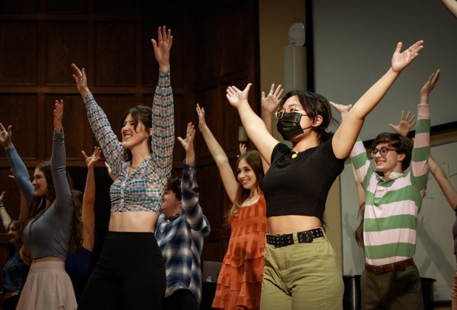 Performers raise their hands and dance onstage.