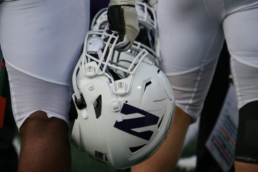 Football player in white uniform holds a white helmet.