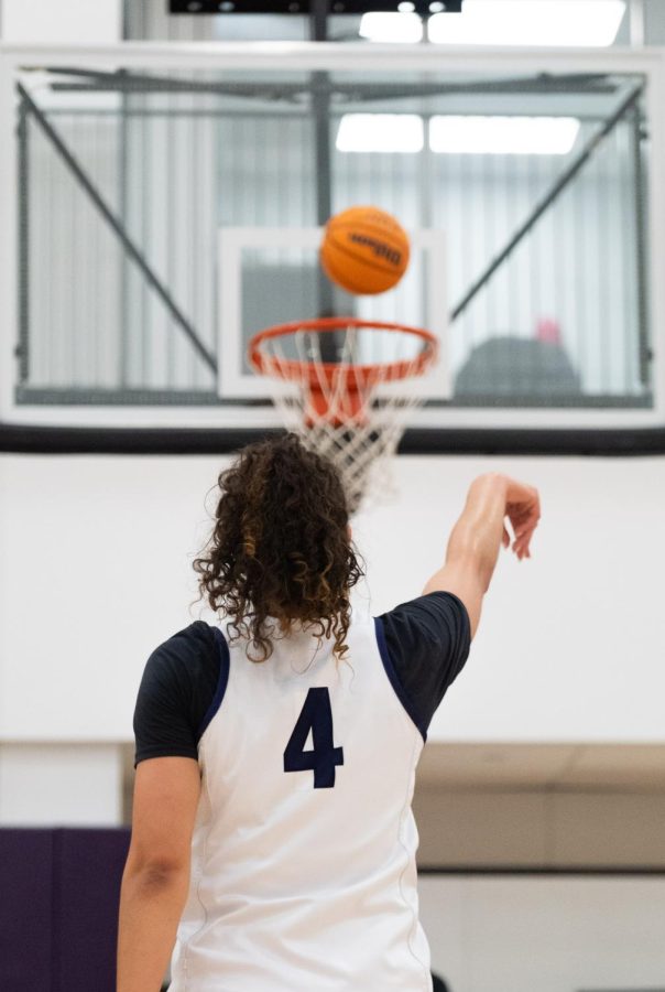 An athlete throws a basketball into a hoop.