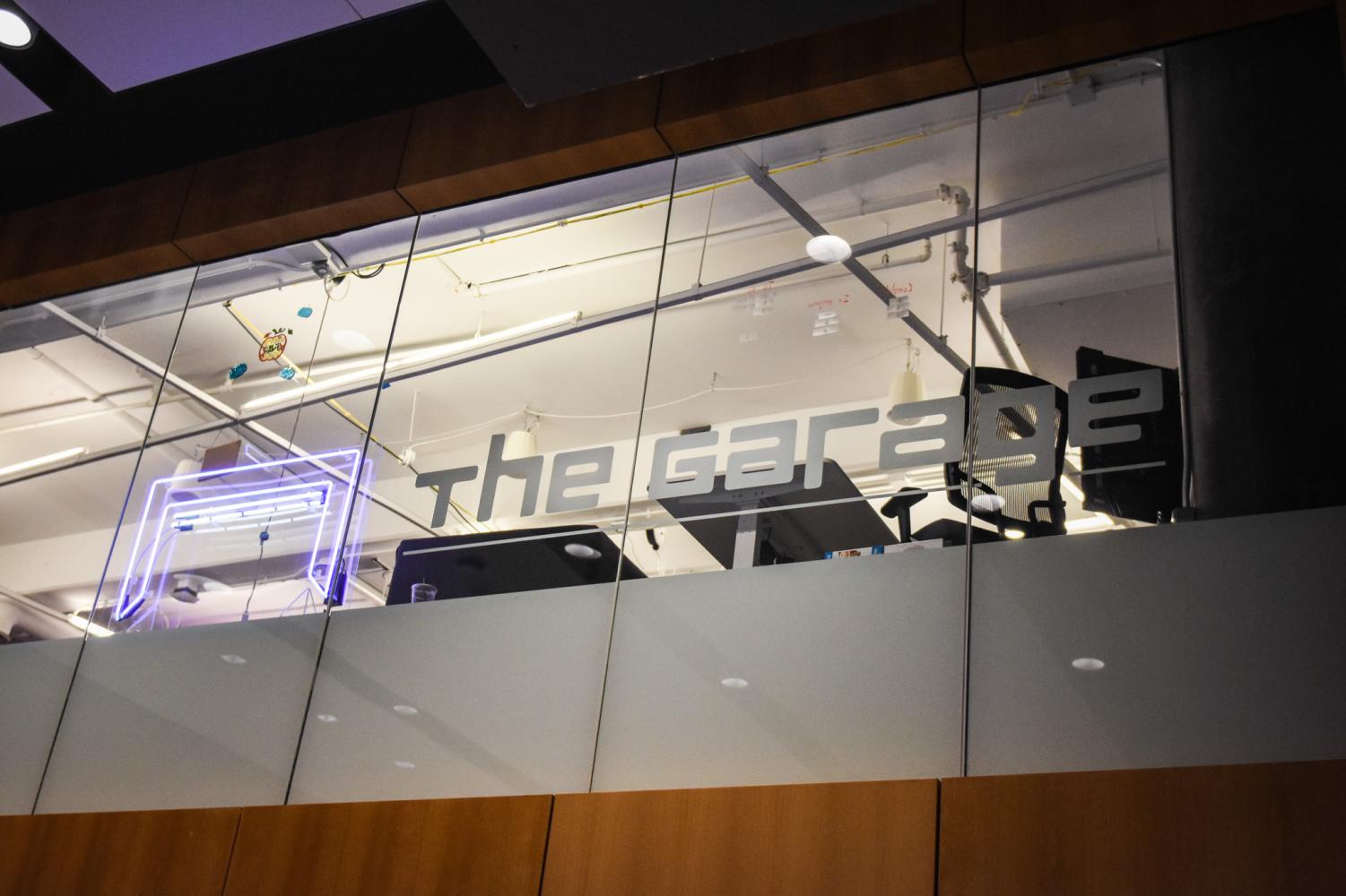 A purple LED-light logo next to the words “The Garage” written in silver on glass panels
