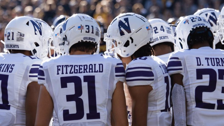 Football players in white jerseys, white pants and white helmets huddle during a game.