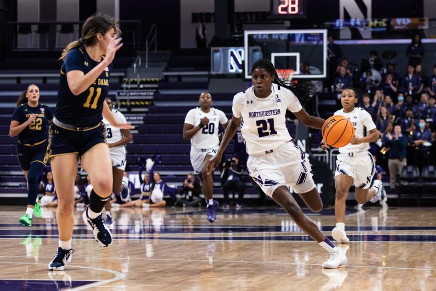 A basketball player wearing white drives down the court.