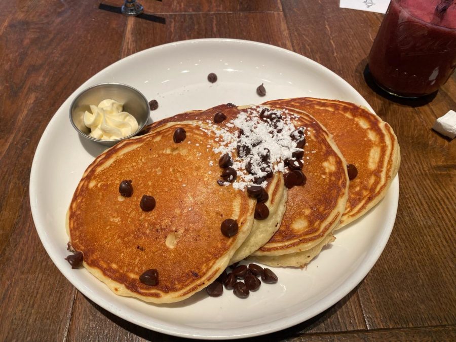 Golden brown pancakes topped with chocolate chips and powdered sugar.