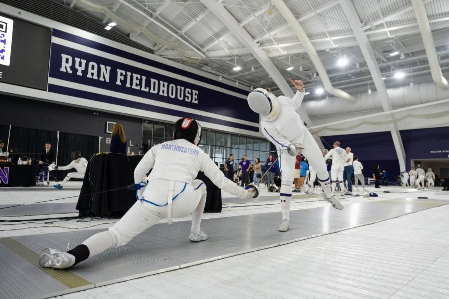 Two fencers in white suits face each other on a mat.