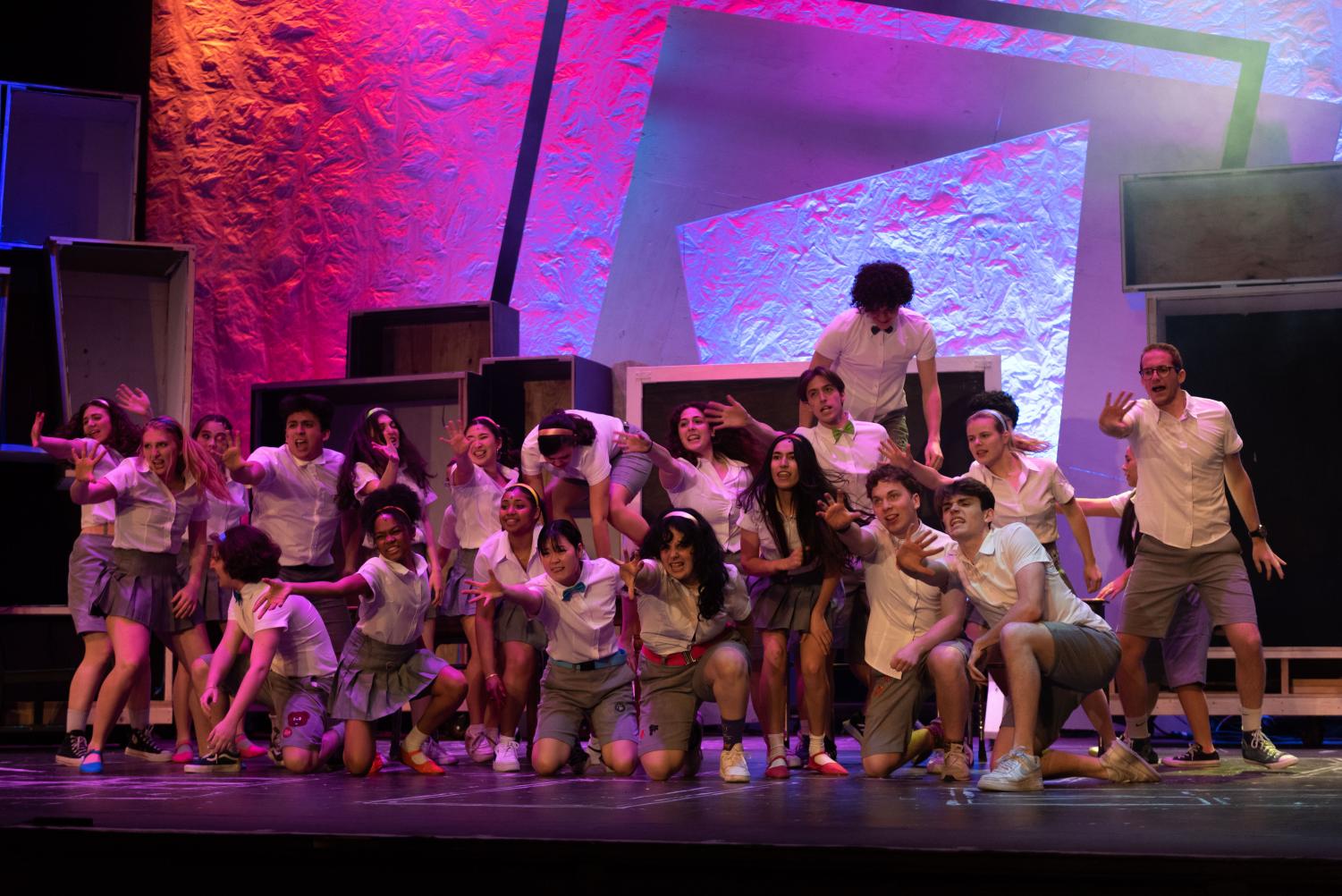 A+group+of+students+wearing+uniforms+dance+on+stage.