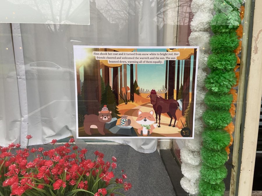 A sign hangs in a window depicting a cartoon fox, bear and horse.
