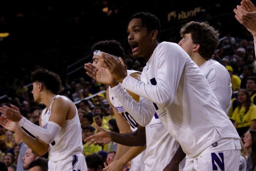 Basketball players in white jerseys cheer on the sidelines.